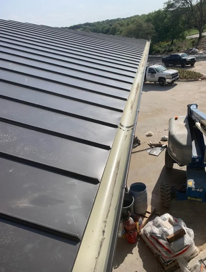 Standing seam panel and gutter detail on a metal roofing jobsite in Saginaw